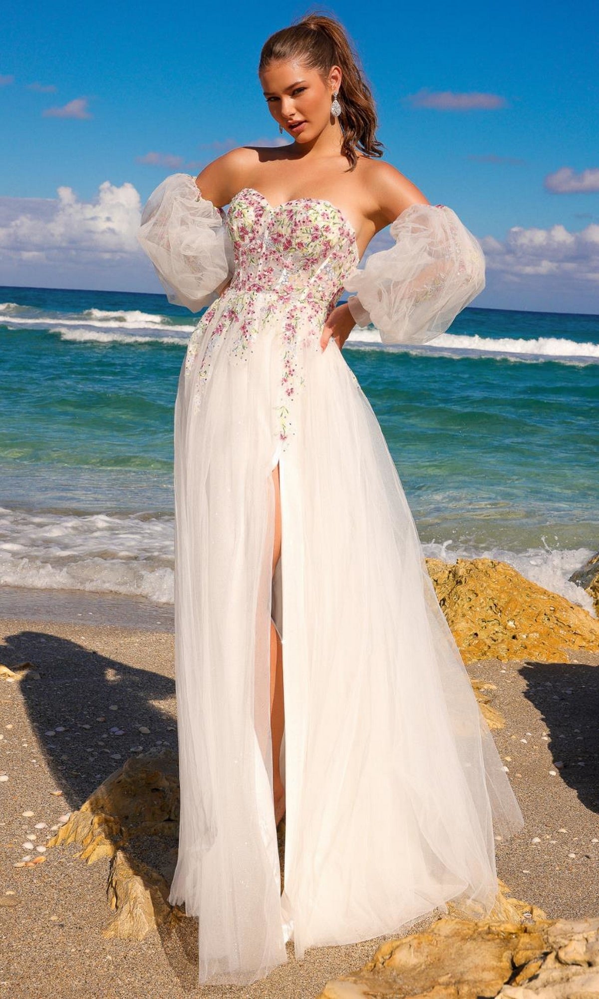 A woman stands on the beach wearing the Long Sleeve Strapless Long Prom Dress SU070, featuring embroidered flowers, sheer removable long sleeves, and a high slit skirt.